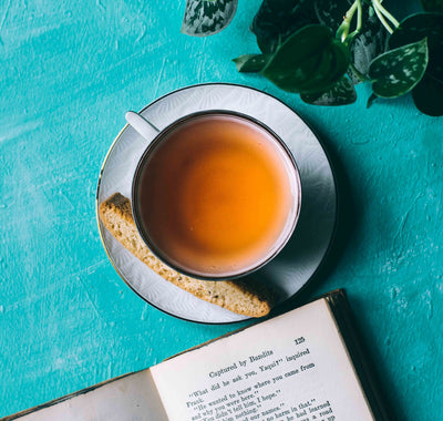 black tea in a tea cup on a blue tablecloth with a book